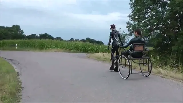 Poster: Latex Pony Outdoor. Female latex pony slave outdoor dominated by her Mistress using her whip to guide her in pulling a cart so that her owner can have fun being carried in this way